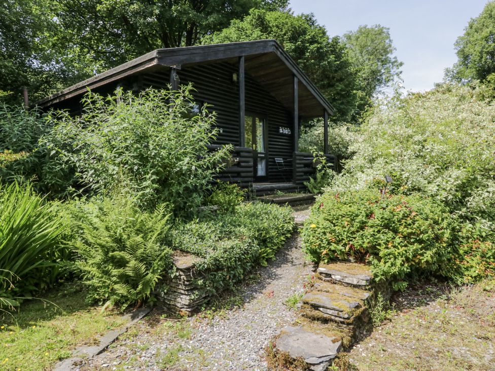 A cabin surrounded by greenery and a stone pathway at Buttermere Spark Bridge near Greenodd
