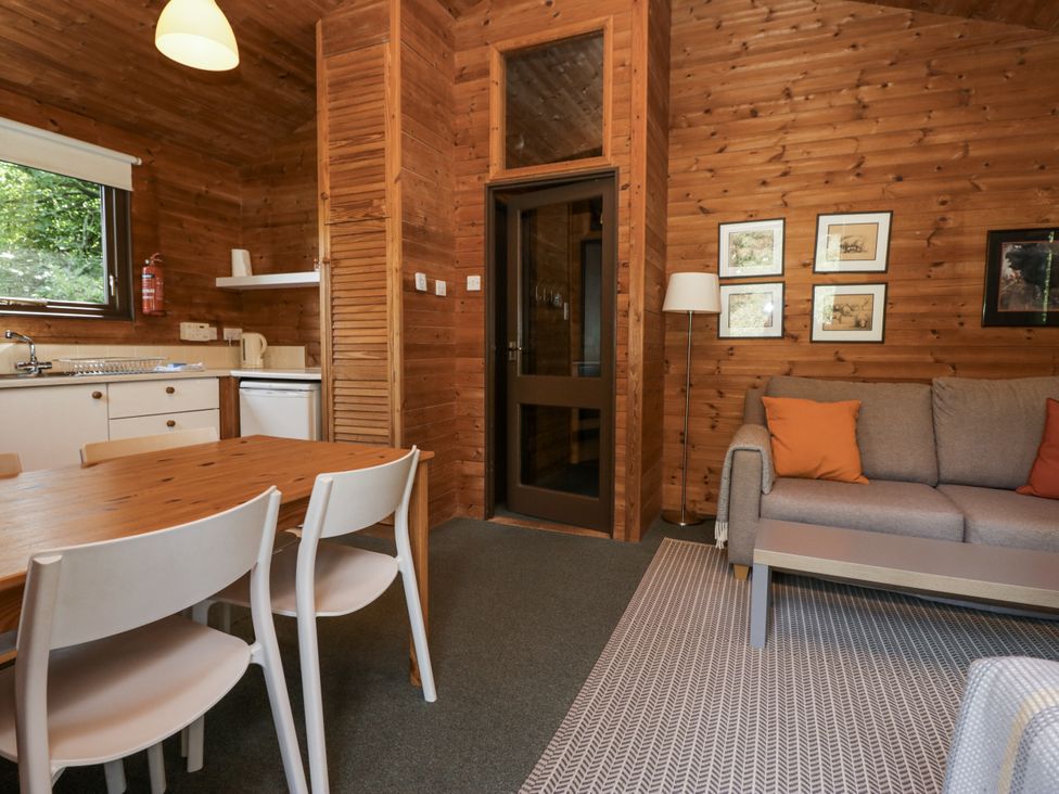 A living room and kitchen area with a dining table and sofa at Buttermere in Spark Bridge near Greenodd