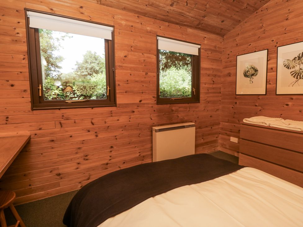 A bedroom with a bed, desk, and windows at Buttermere near Spark Bridge