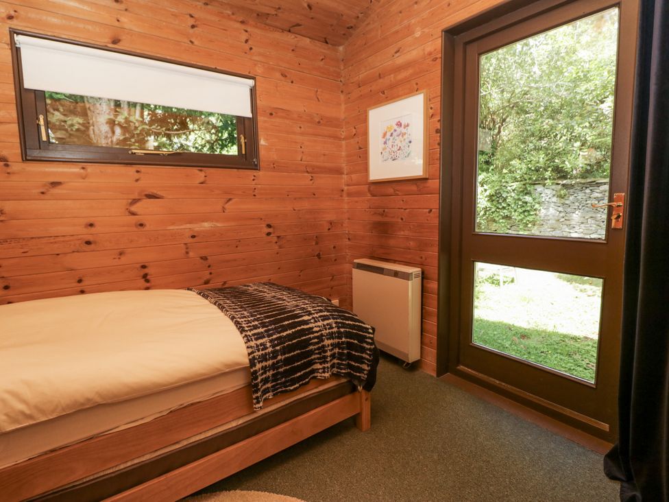 A bedroom with a bed and a door leading outside at Grasmere in Spark Bridge near Greenodd