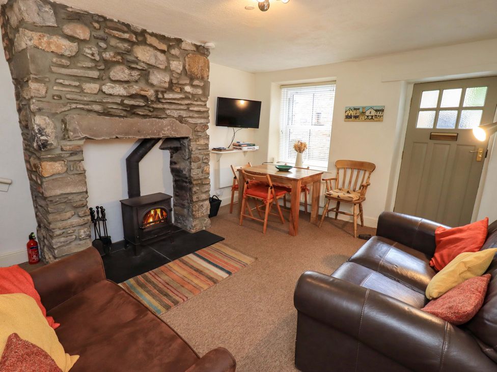 A living room with a stone fireplace and wood stove at Back Cottage in Kirkby Lonsdale