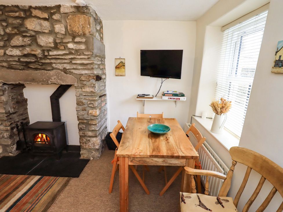 A dining room with a wooden table and stove at Back Cottage in Kirkby Lonsdale