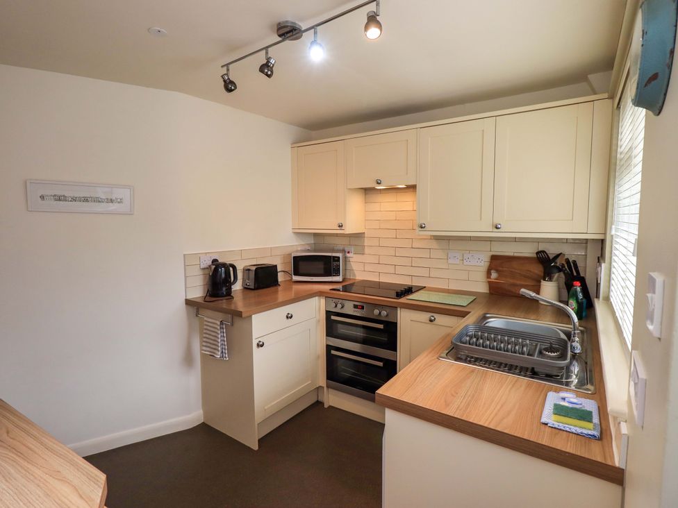 A kitchen with cabinets, sink, stove, and appliances at Back Cottage in Kirkby Lonsdale