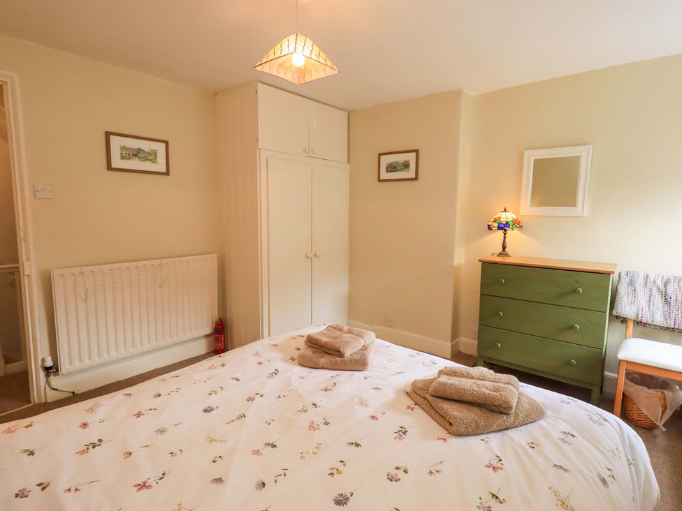 A bedroom with a bed and dresser at Back Cottage in Kirkby Lonsdale