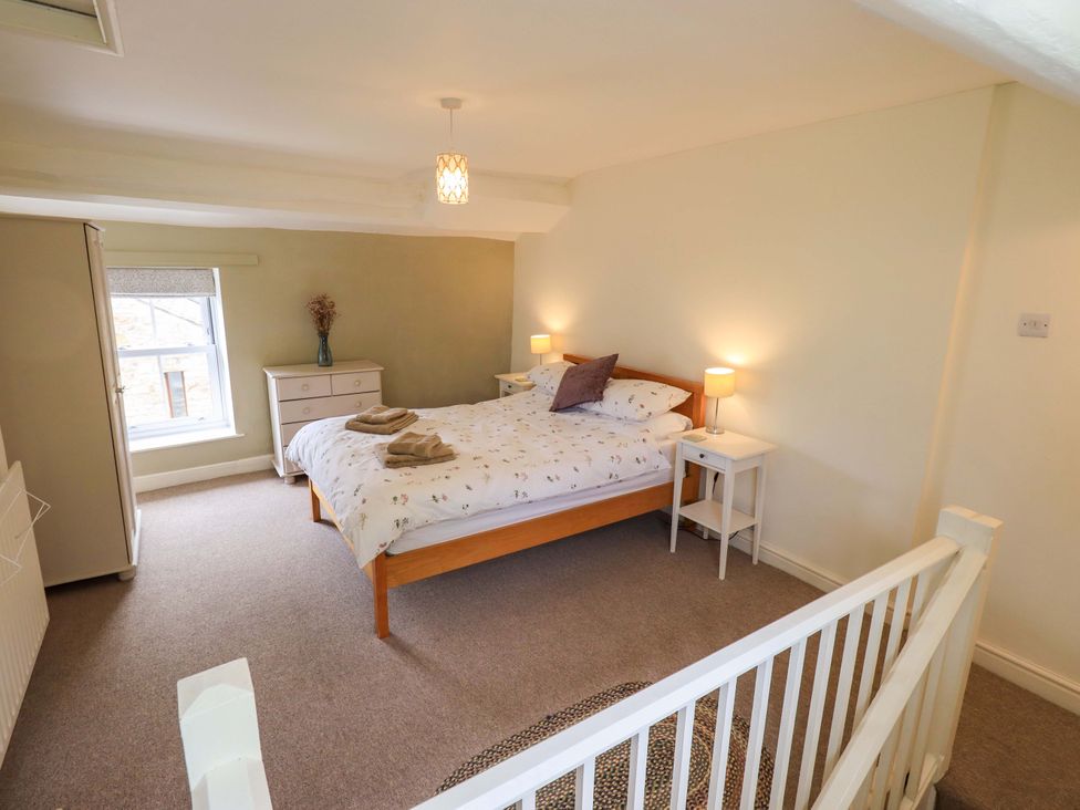 A bedroom with a bed and nightstands at Back Cottage in Kirkby Lonsdale