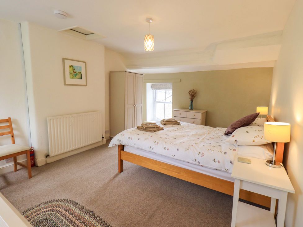 A bedroom with a bed and dresser at Back Cottage in Kirkby Lonsdale