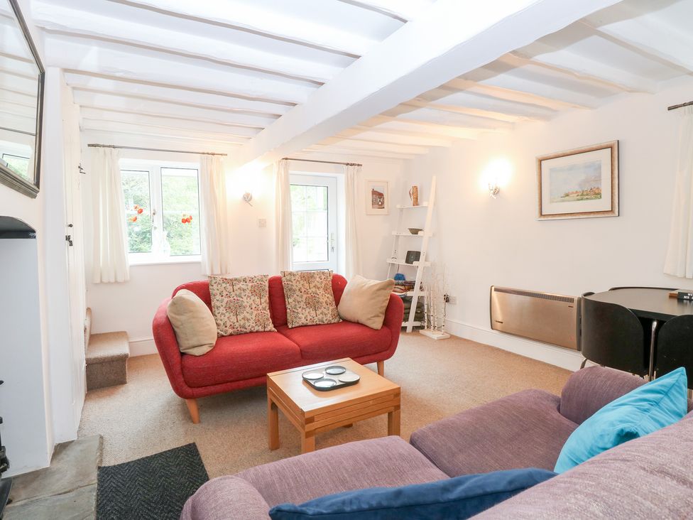 A living room with a red sofa and coffee table at Broom Cottage in East Rudham near Fakenham