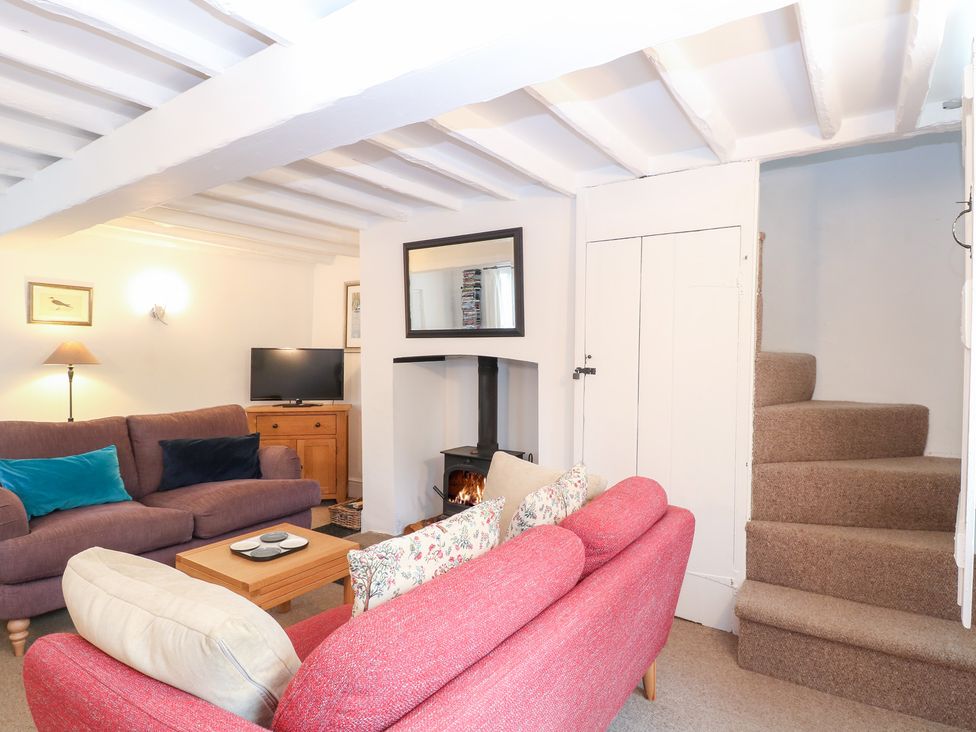A living room with a sofa, armchair, and television at Broom Cottage in East Rudham near Fakenham