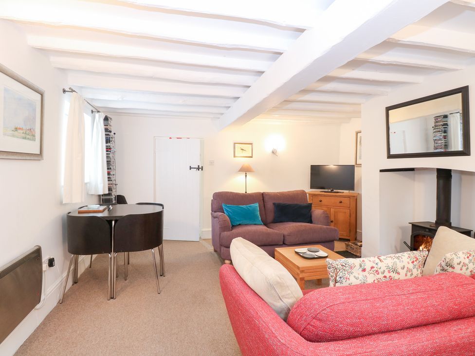 A living room with a sofa, armchair, and table at Broom Cottage in East Rudham near Fakenham