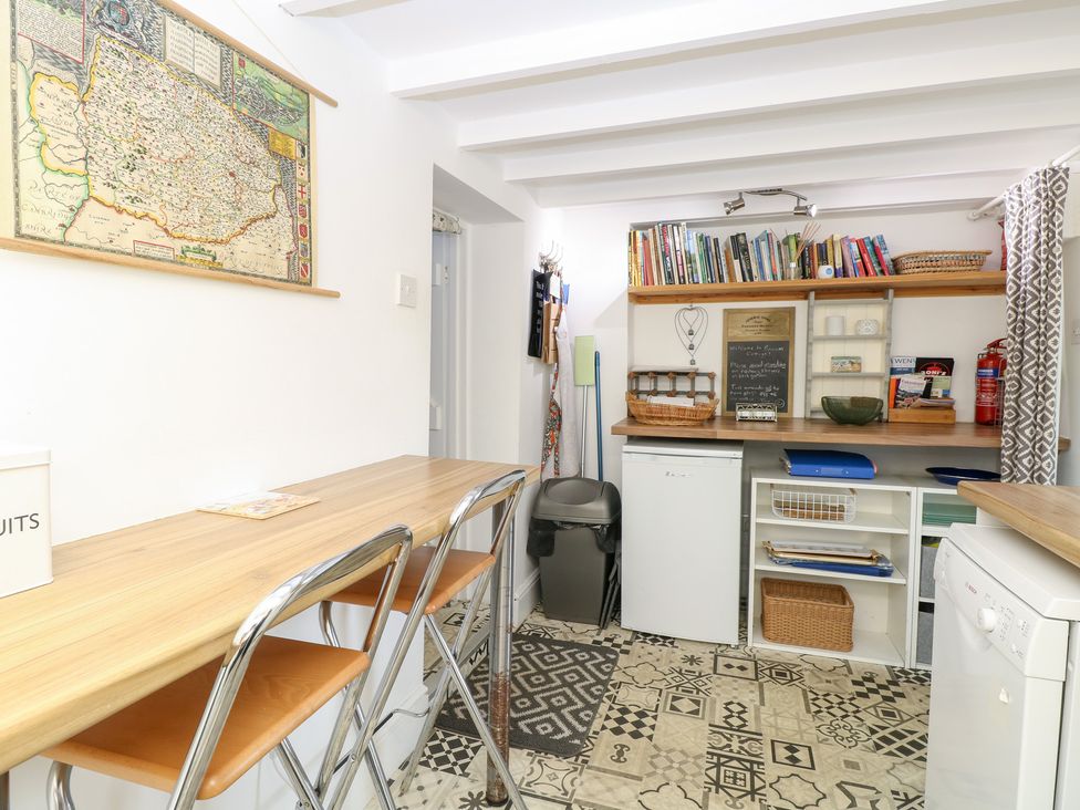 A kitchen with a table and bar stools at Broom Cottage in East Rudham near Fakenham