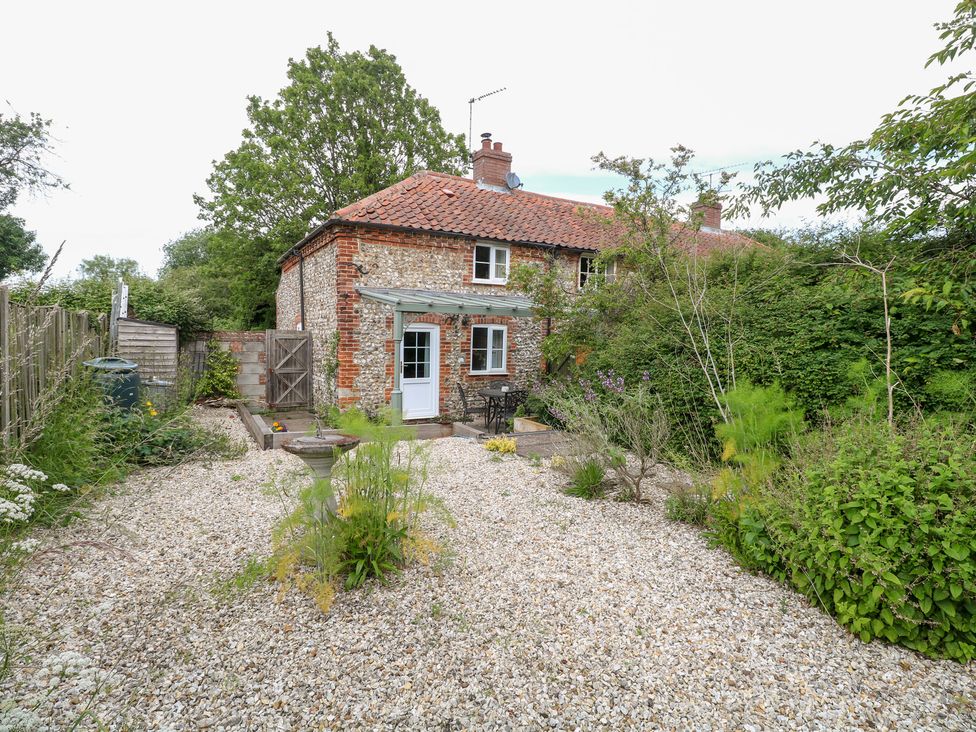 A cottage with gravel garden and table with chairs at Broom Cottage in East Rudham near Fakenham