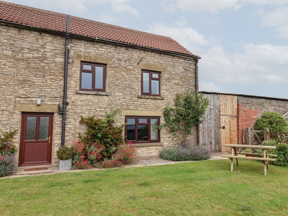 A stone house with a garden and picnic table at Wethercote Cottage Old Byland near Helmsley