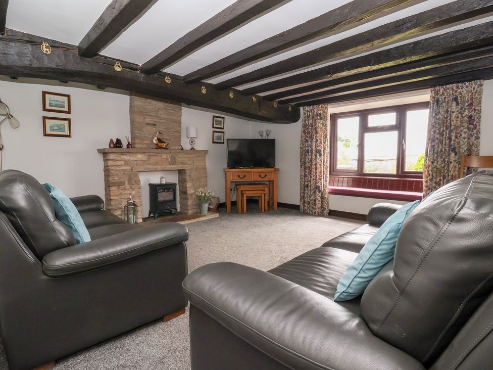 A living room with a fireplace and television at Wethercote Cottage in Old Byland near Helmsley
