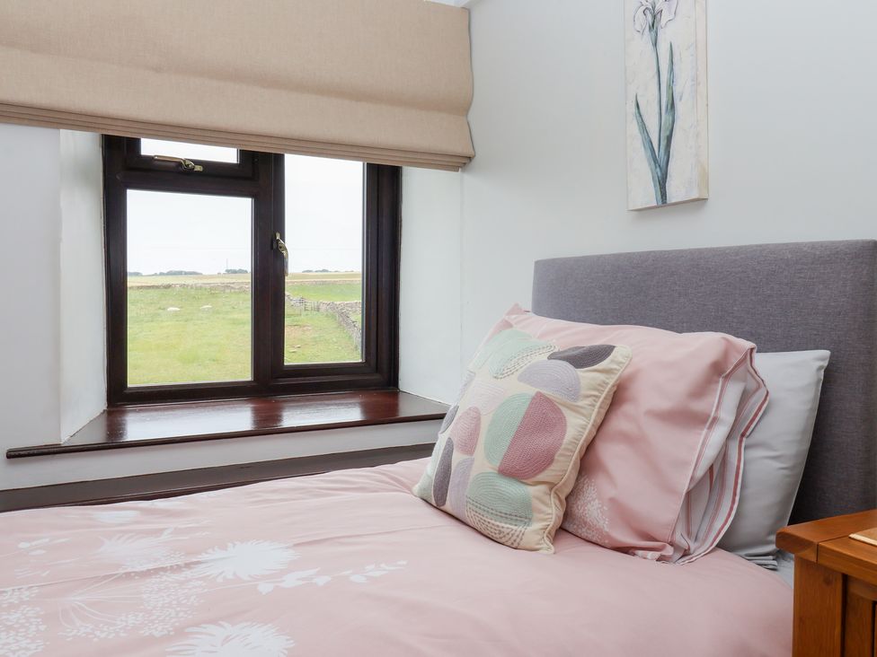 A bedroom with a bed and window at Wethercote Cottage in Old Byland near Helmsley