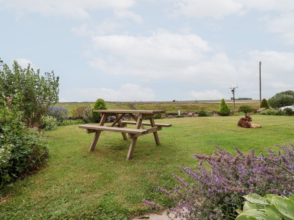 A garden with a picnic table and flowers at Wethercote Cottage in Old Byland near Helmsley
