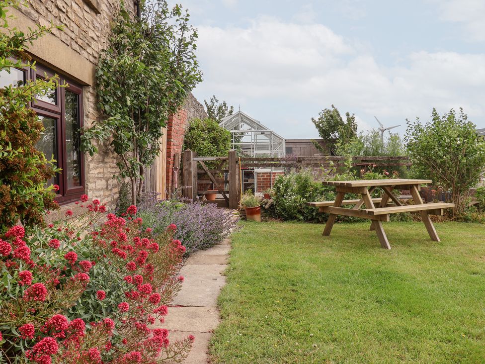 A garden with flowers, a pathway, and a table at Wethercote Cottage in Old Byland near Helmsley