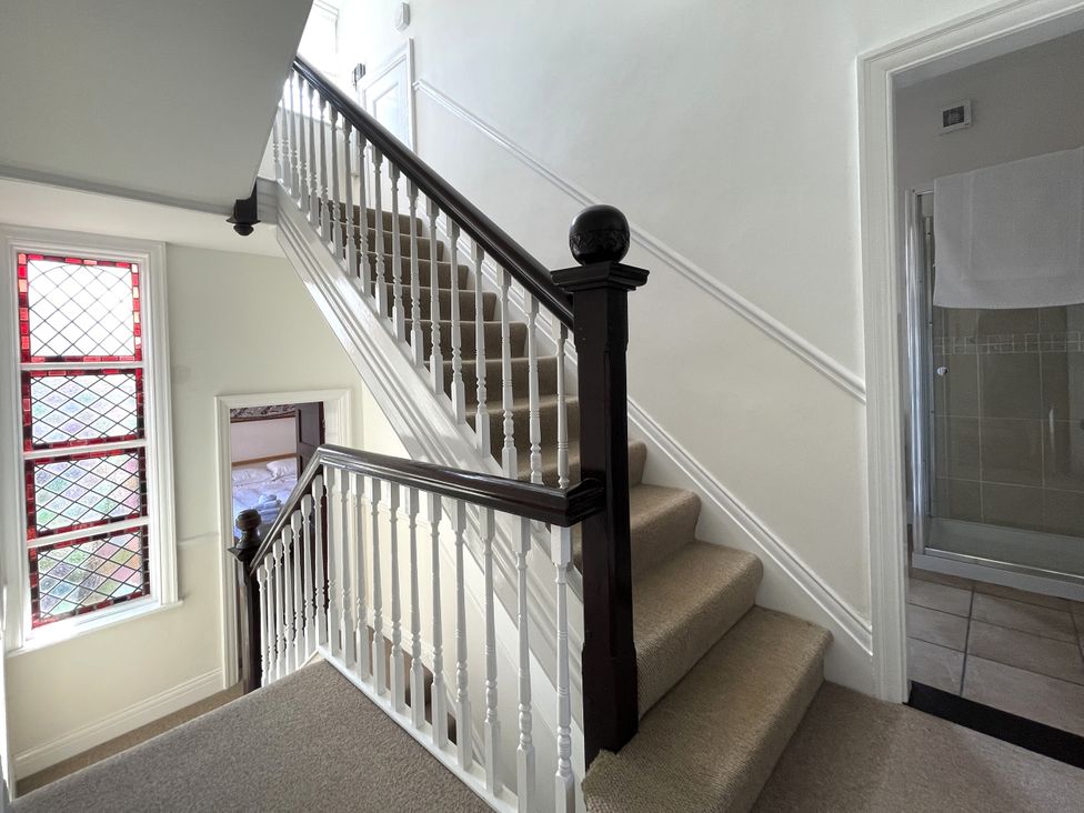 A staircase with a stained glass window and bathroom door at Sterling House in Robin Hood's Bay
