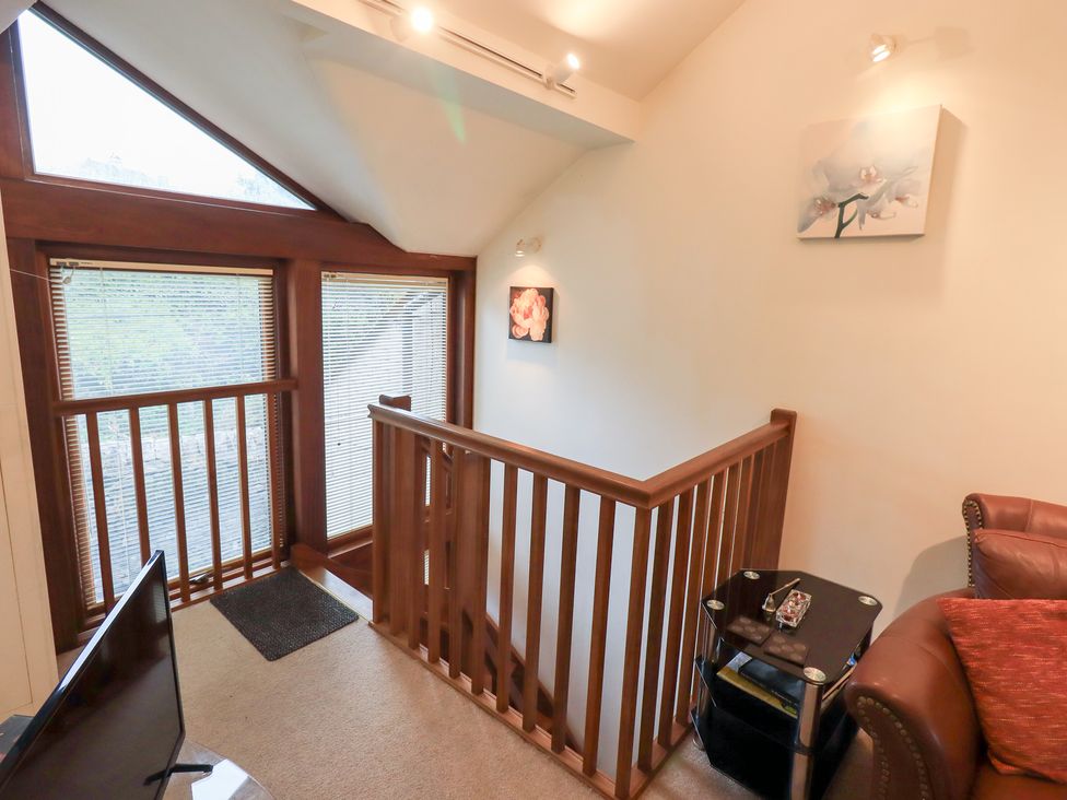 A staircase with a railing and a small table at Wood Cottage Kendal
