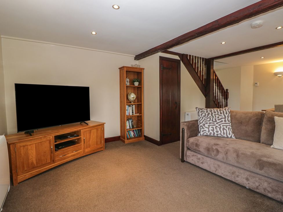 A living room with a television and a bookshelf at Woodside Barn Pennington near Ulverston