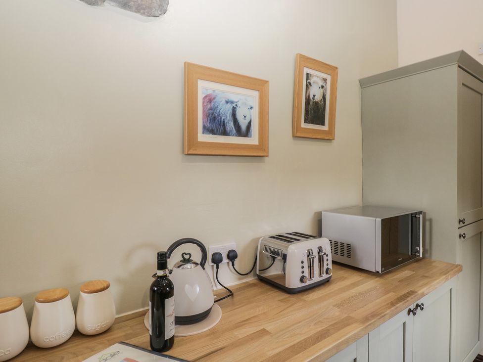 A kitchen with a kettle, toaster, wine bottle, and microwave at Woodside Barn Pennington near Ulverston