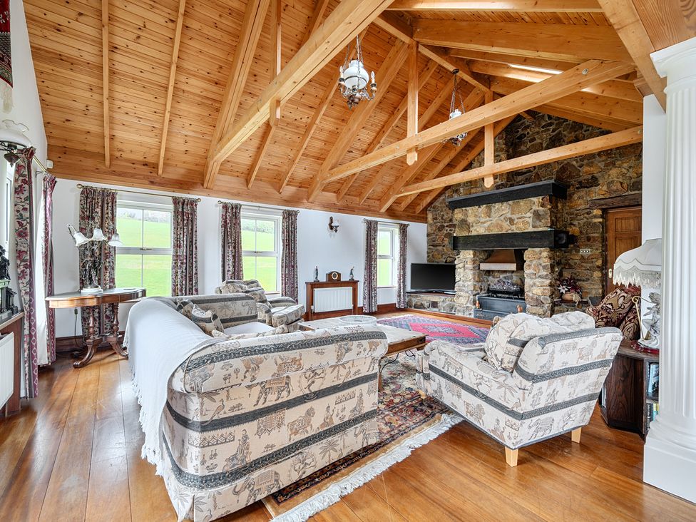 A living room with sofas, a coffee table, and a fireplace at Chapel Green in Polgooth