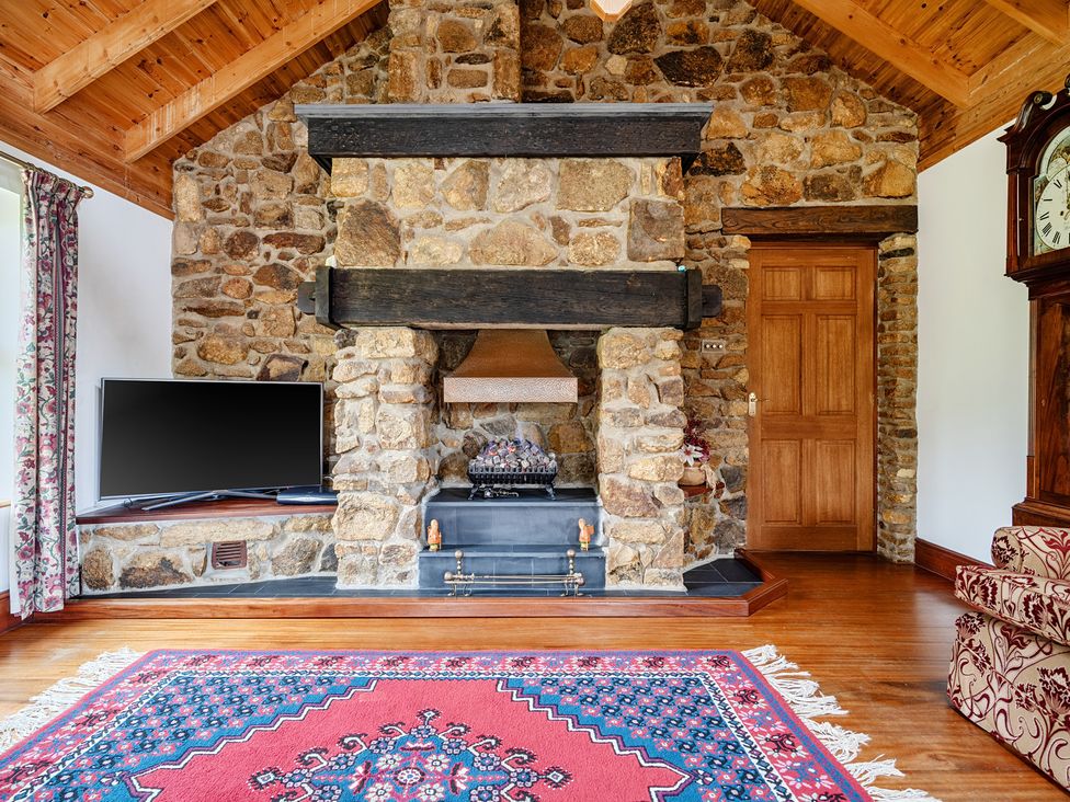 A living room with a fireplace and television at Chapel Green in Polgooth