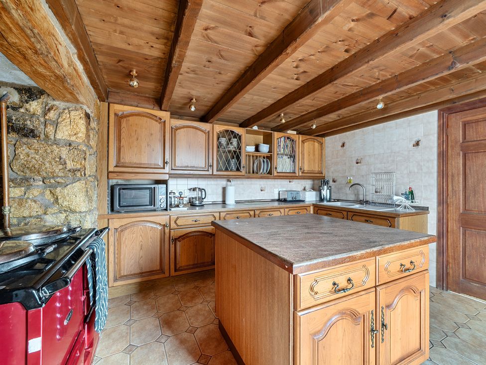 A kitchen with wooden cabinets and appliances at Chapel Green in Polgooth