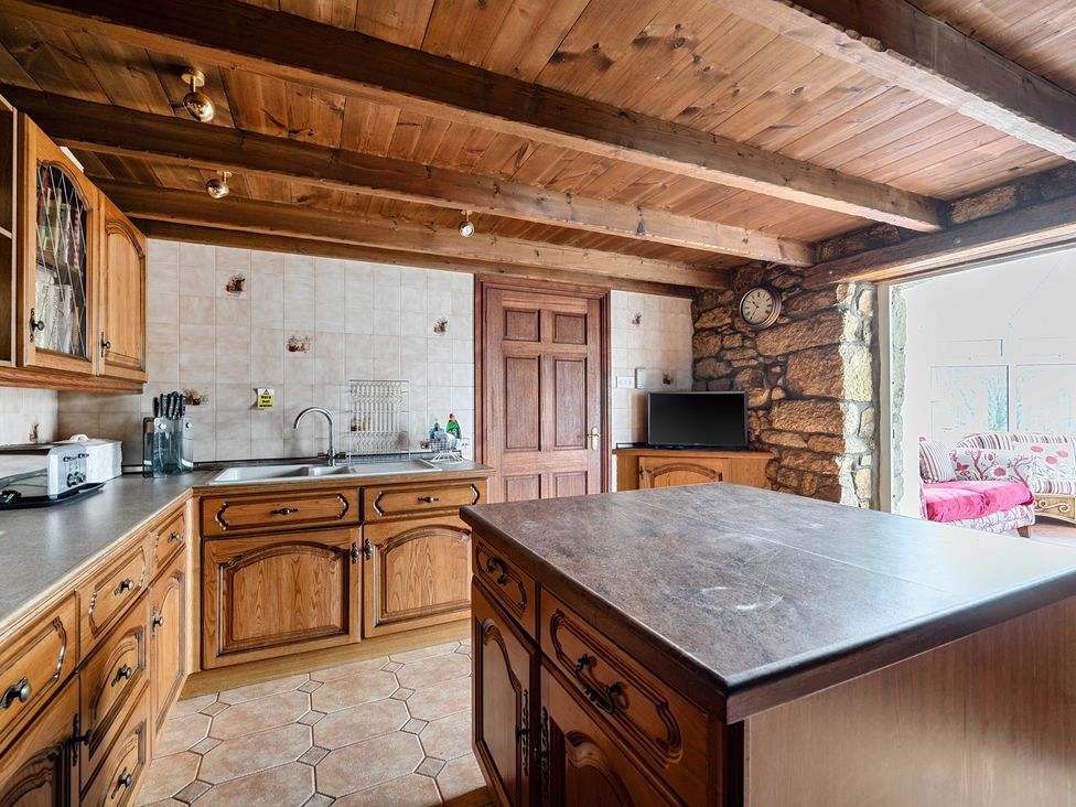 A kitchen with wooden cabinets and a sink at Chapel Green in Polgooth