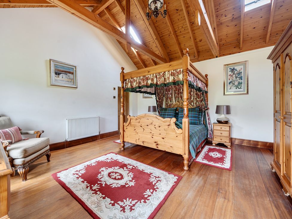 A bedroom with a four-poster bed and armchair at Chapel Green in Polgooth