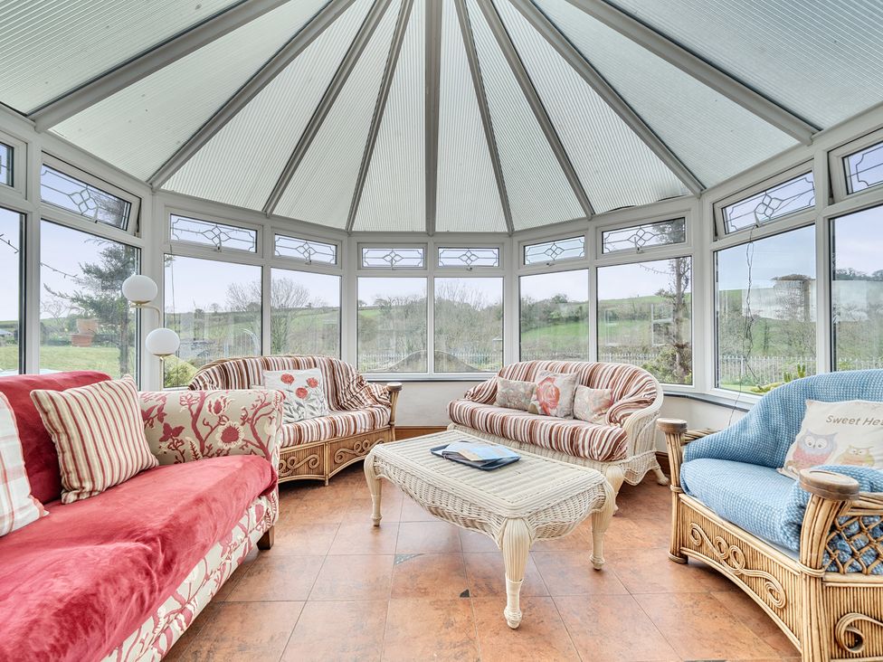 A conservatory with sofas and a coffee table at Chapel Green in Polgooth