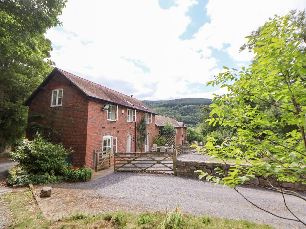 A house with a gate and driveway surrounded by trees at Bryn Howell Stables Trevor near Llangollen
