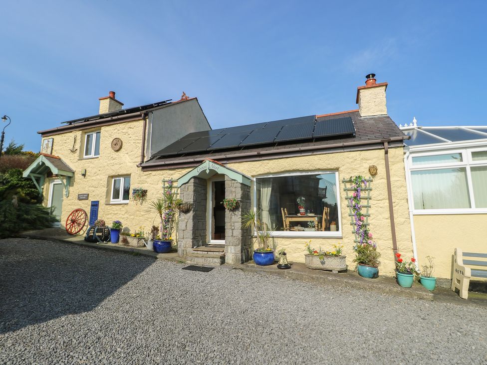 A house with solar panels and potted plants at Crow's Nest Cottage in Tynygongl near Benllech