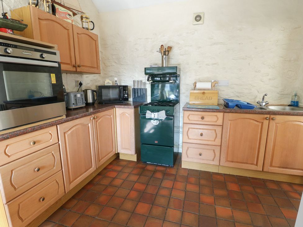 A kitchen with cabinets, appliances, and a sink at Crow's Nest Cottage in Tynygongl near Benllech
