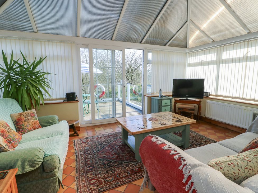 A conservatory with sofas and a table at Crow's Nest Cottage Tynygongl near Benllech