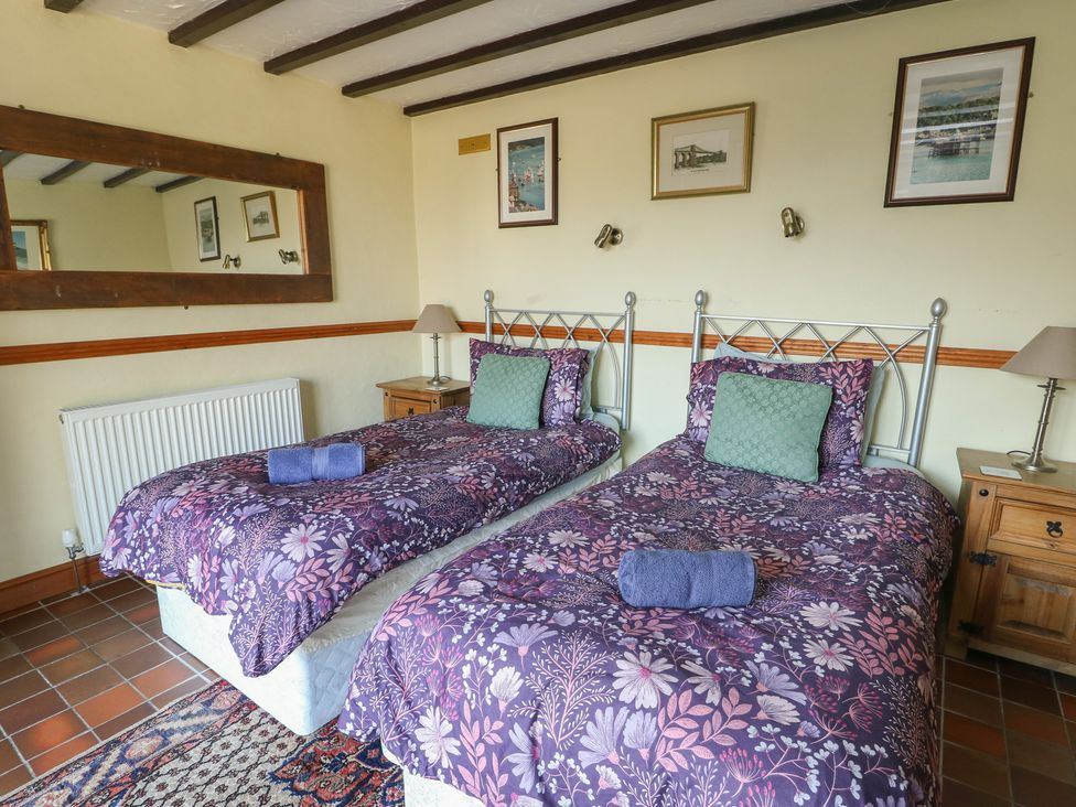 A bedroom with twin beds and a bedside table at Crow's Nest Cottage Tynygongl near Benllech