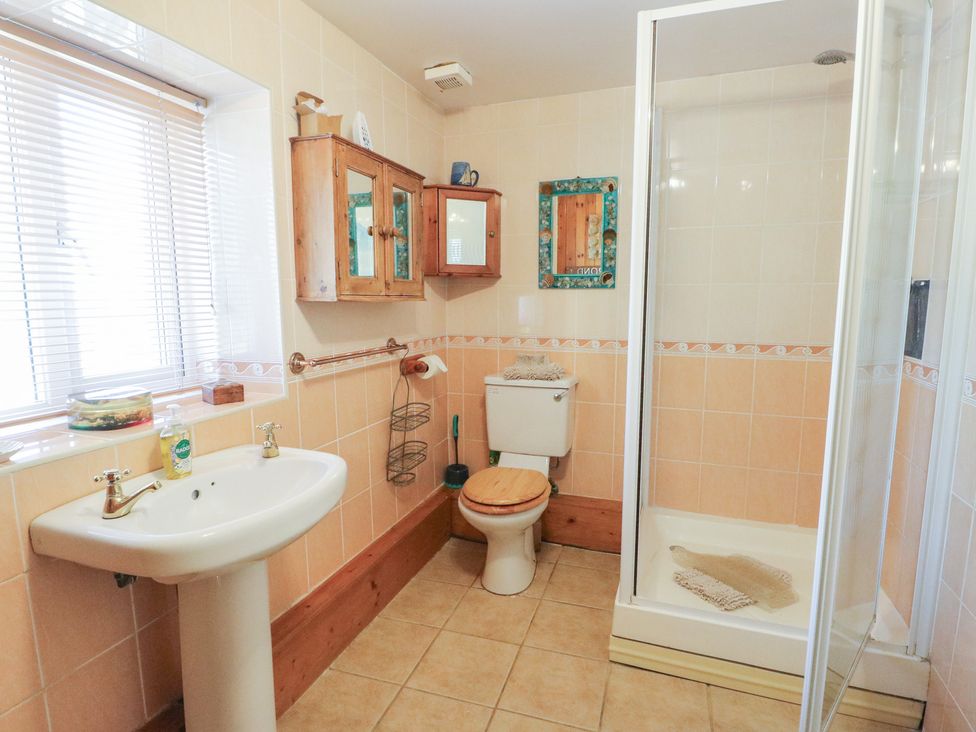 A bathroom with a sink, shower, and toilet at Crow's Nest Cottage in Tynygongl near Benllech