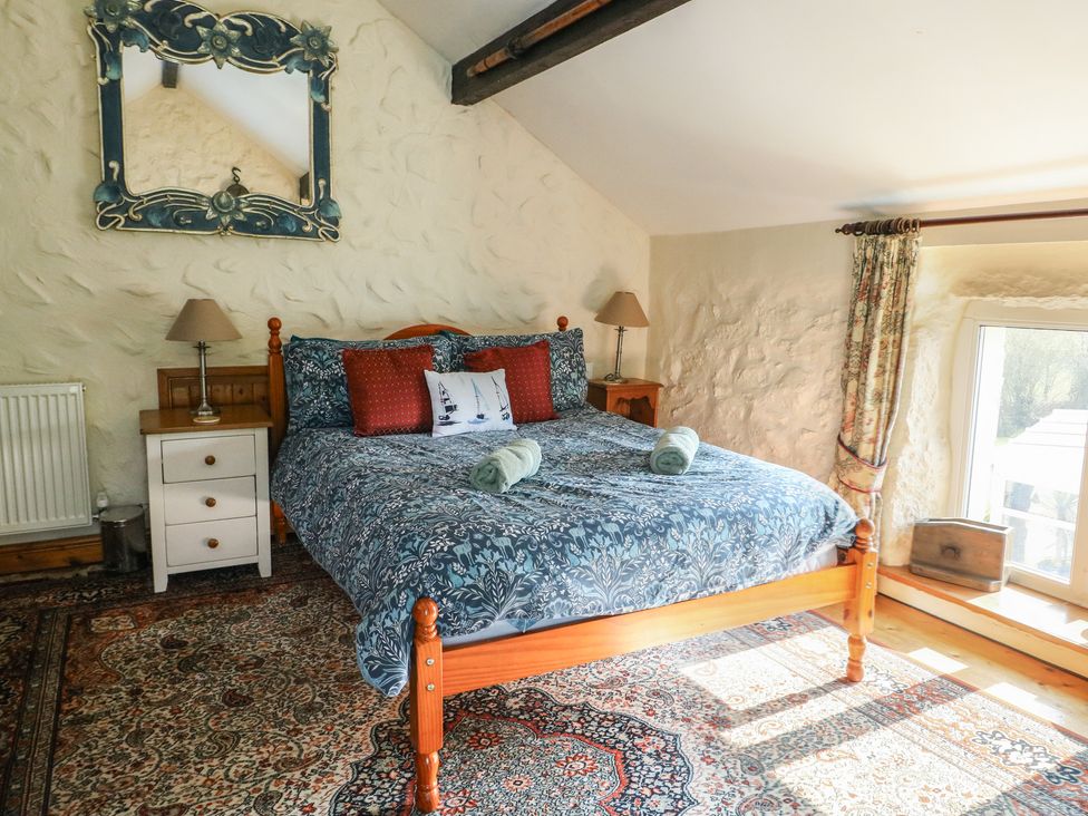 A bedroom with a bed and bedside table at Crow's Nest Cottage Tynygongl near Benllech