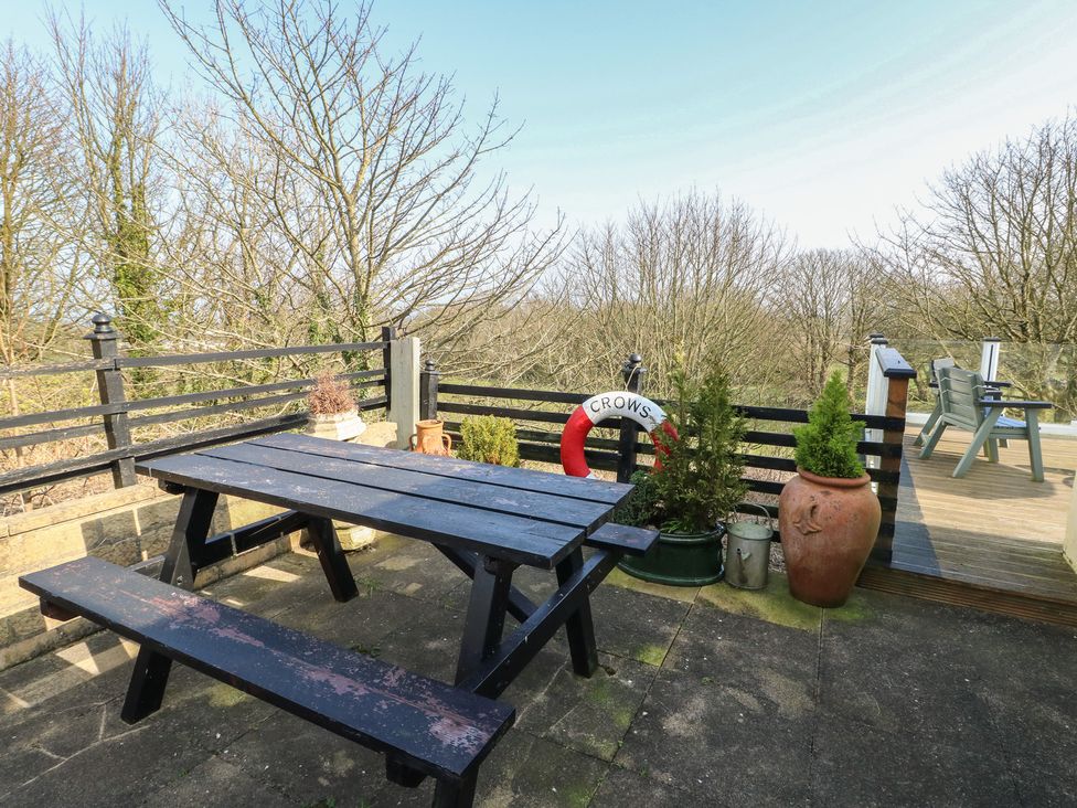 An outdoor area with a table and benches at Crow's Nest Cottage in Tynygongl near Benllech