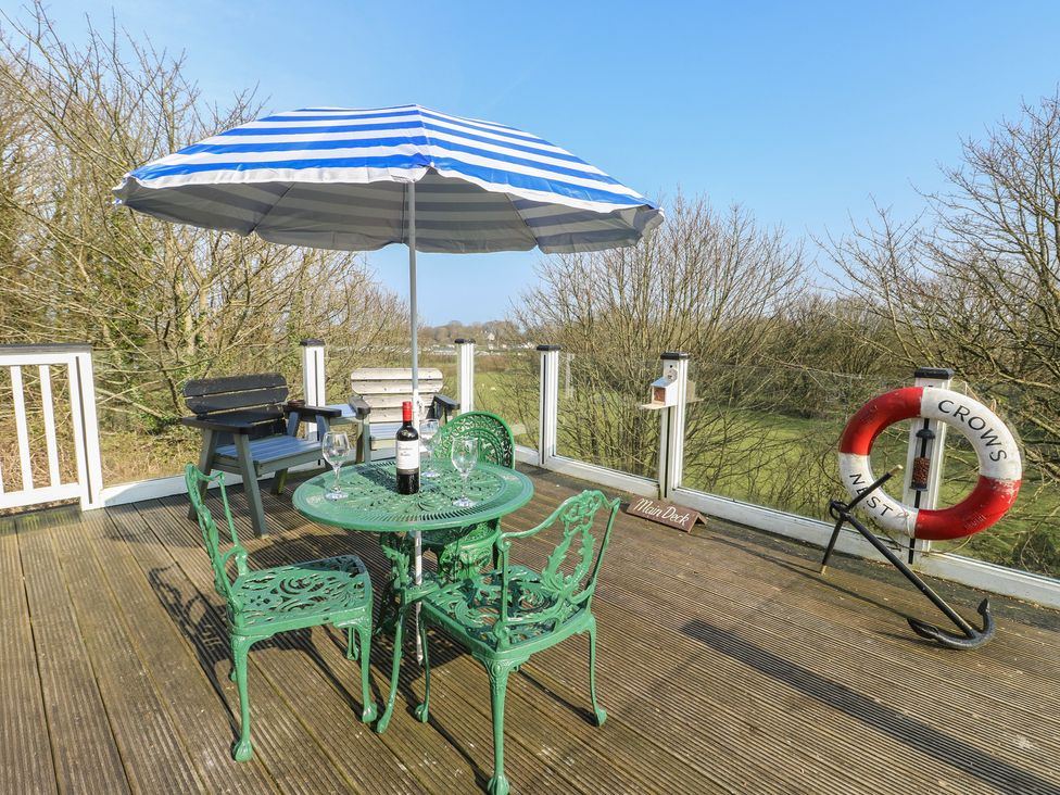 An outdoor seating area with a table and chairs at Crow's Nest Cottage in Tynygongl near Benllech