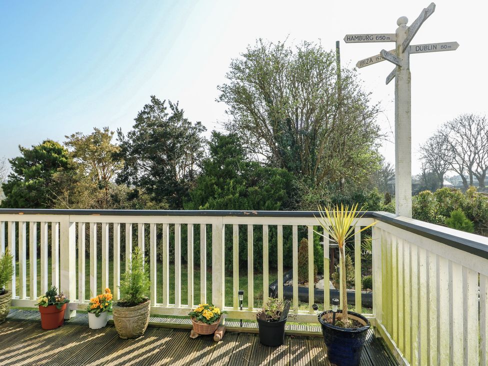 A balcony with potted plants and a directional sign at Crow's Nest Cottage Tynygongl near Benllech
