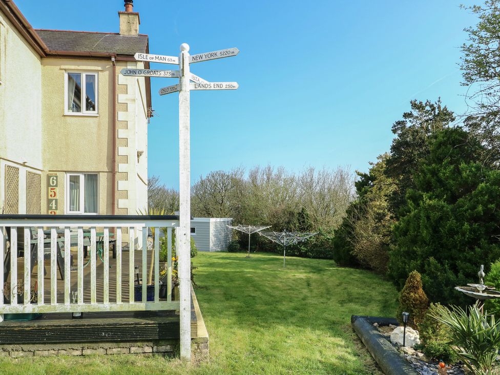 An outdoor signpost with various locations and a garden at Crow's Nest Cottage Tynygongl near Benllech