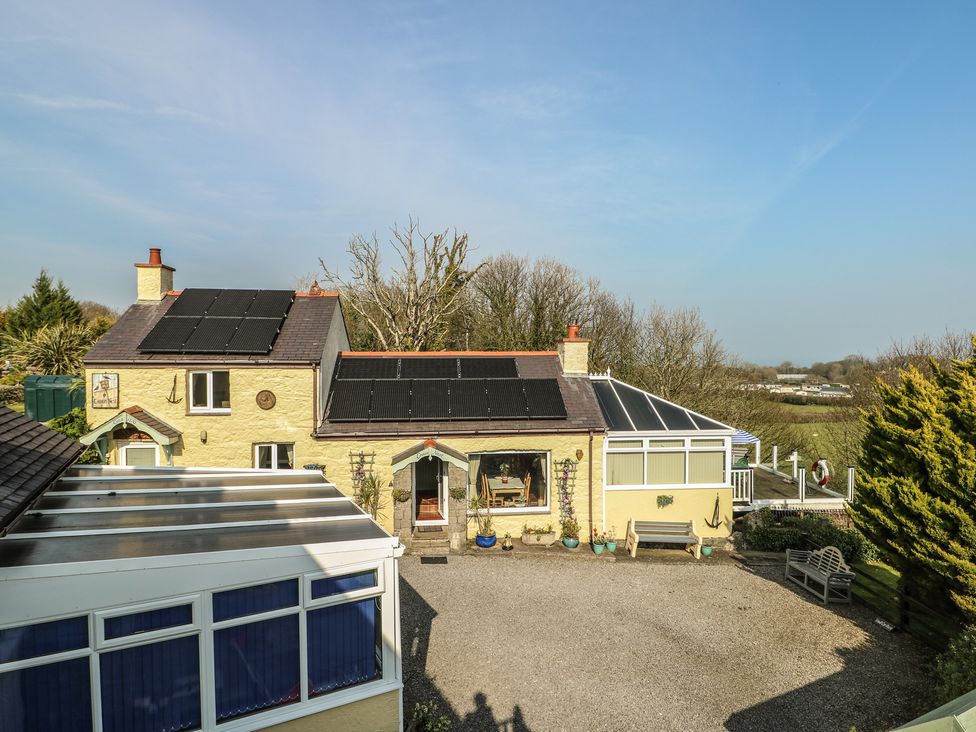 A house with solar panels and a patio area at Crow's Nest Cottage Tynygongl near Benllech