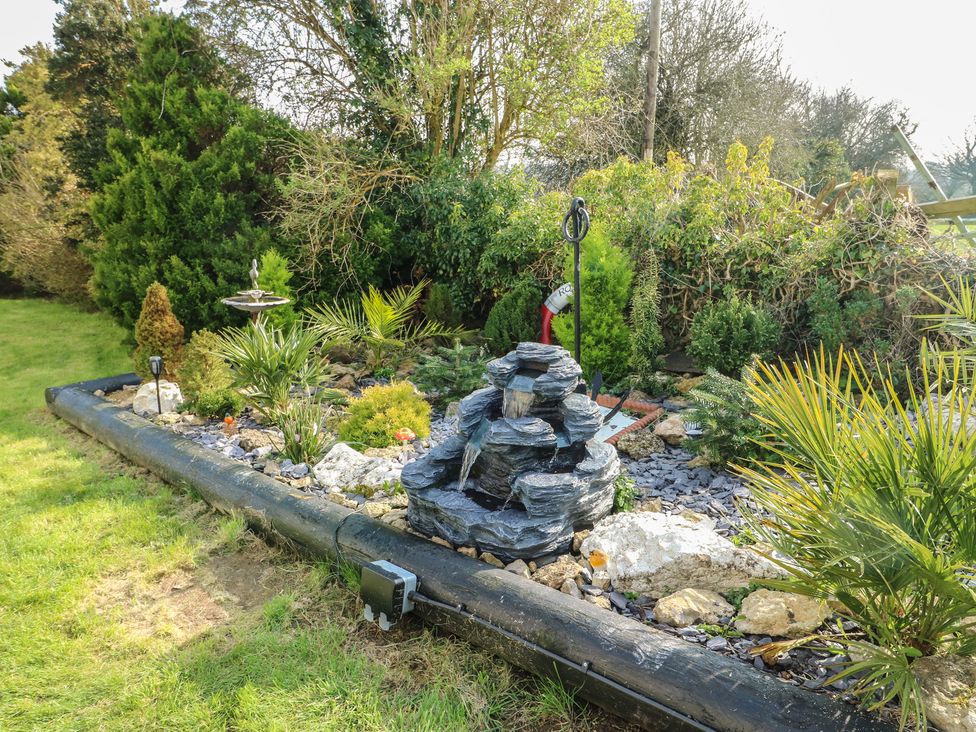 A garden with a fountain and various plants at Crow's Nest Cottage Tynygongl near Benllech