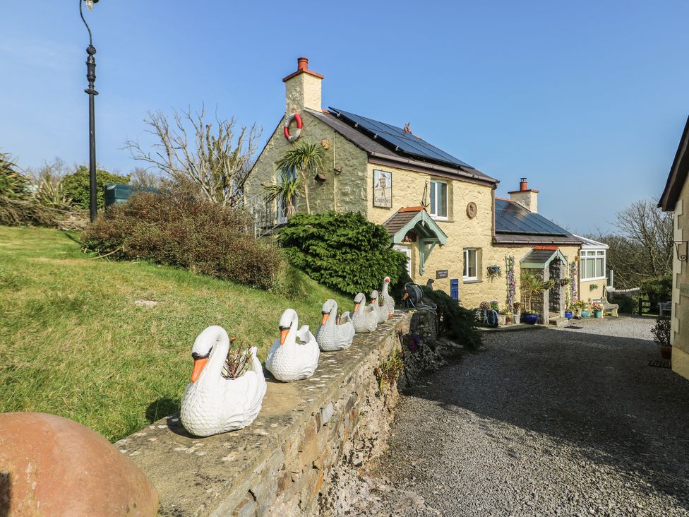 An outdoor photo of a house with a garden and decorative swans at Crow's Nest Cottage Tynygongl near Benllech