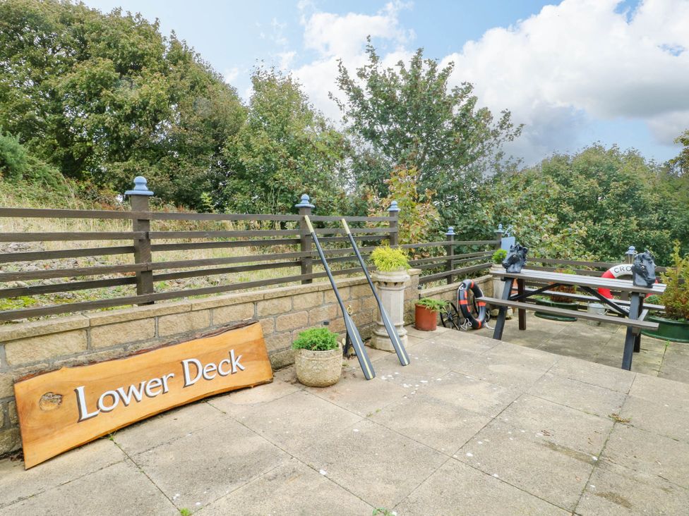 An outdoor patio area with a wooden sign and seating at Crow's Nest Cottage in Tynygongl near Benllech