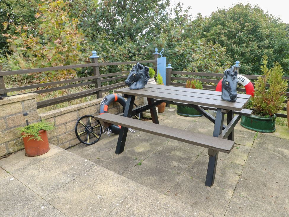 An outdoor seating area with a picnic table and decorative items at Crow's Nest Cottage Tynygongl near Benllech
