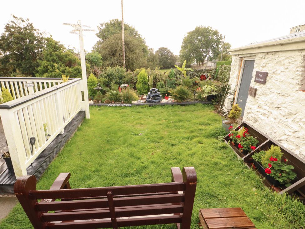 A garden with a bench and flower pots at Crow's Nest Cottage Tynygongl near Benllech