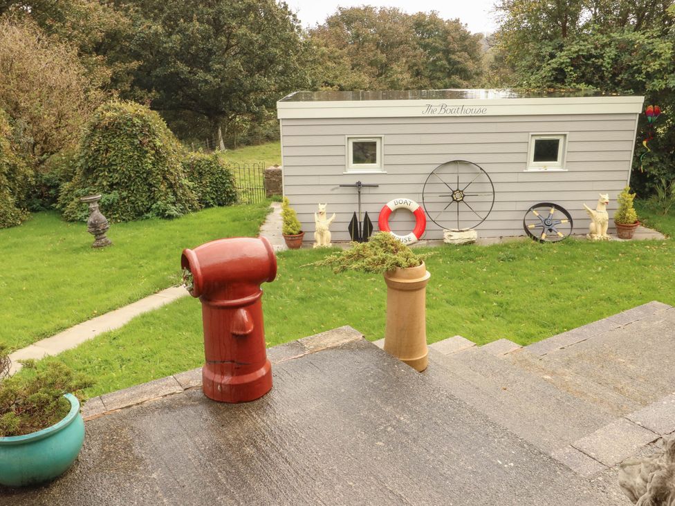 A garden with a boathouse and decorative objects at Crow's Nest Cottage Tynygongl near Benllech