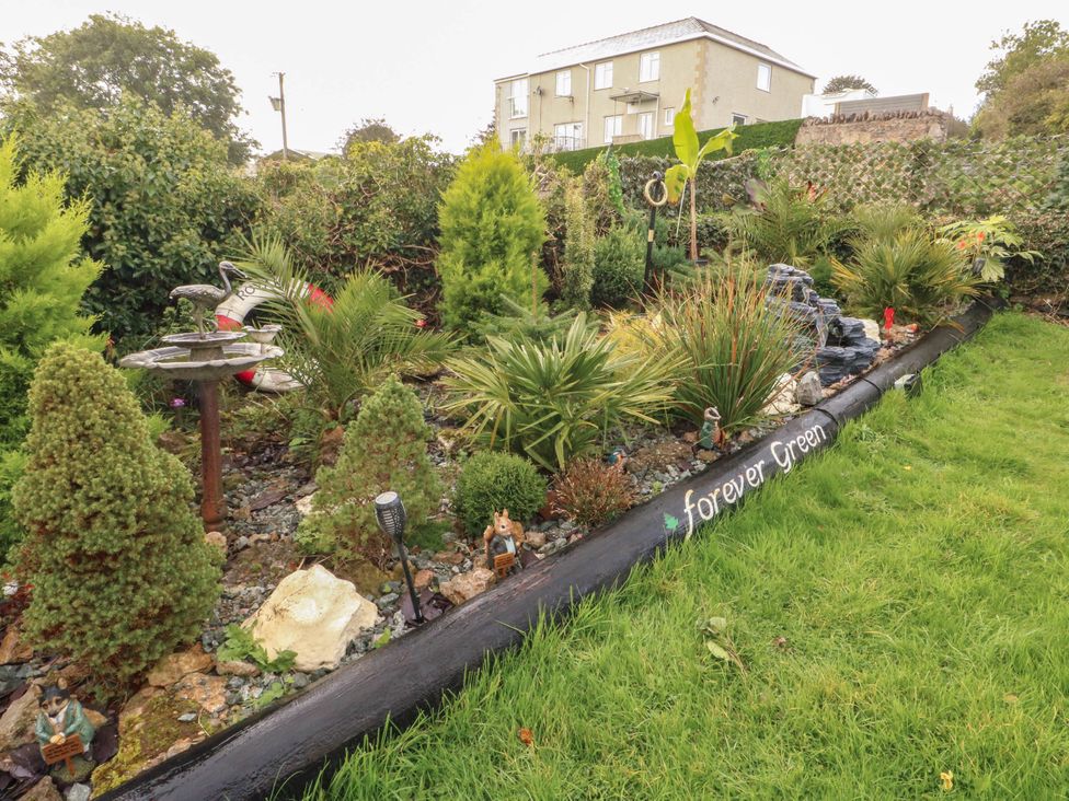 A garden with various plants and decorative features at Crow's Nest Cottage in Tynygongl near Benllech