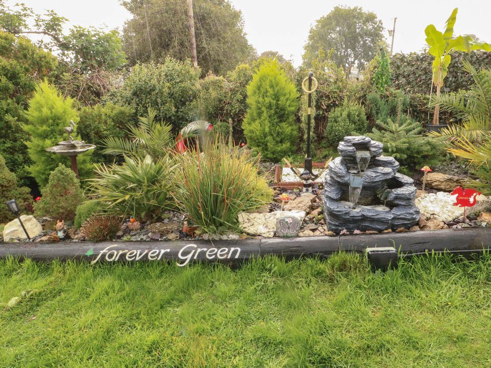 A garden featuring a fountain and various plants at Crow's Nest Cottage in Tynygongl near Benllech